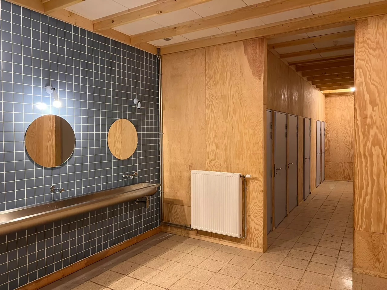 Espaces sanitaires du bâtiment démonstrateur de Noeux-environnement, associant parements bois biosourcés et carrelage mural, pour allier fonctionnalité, durabilité et cohérence architecturale.